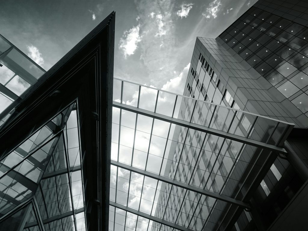 Low angle view of modern glass facade buildings showcasing contemporary architecture with reflections.